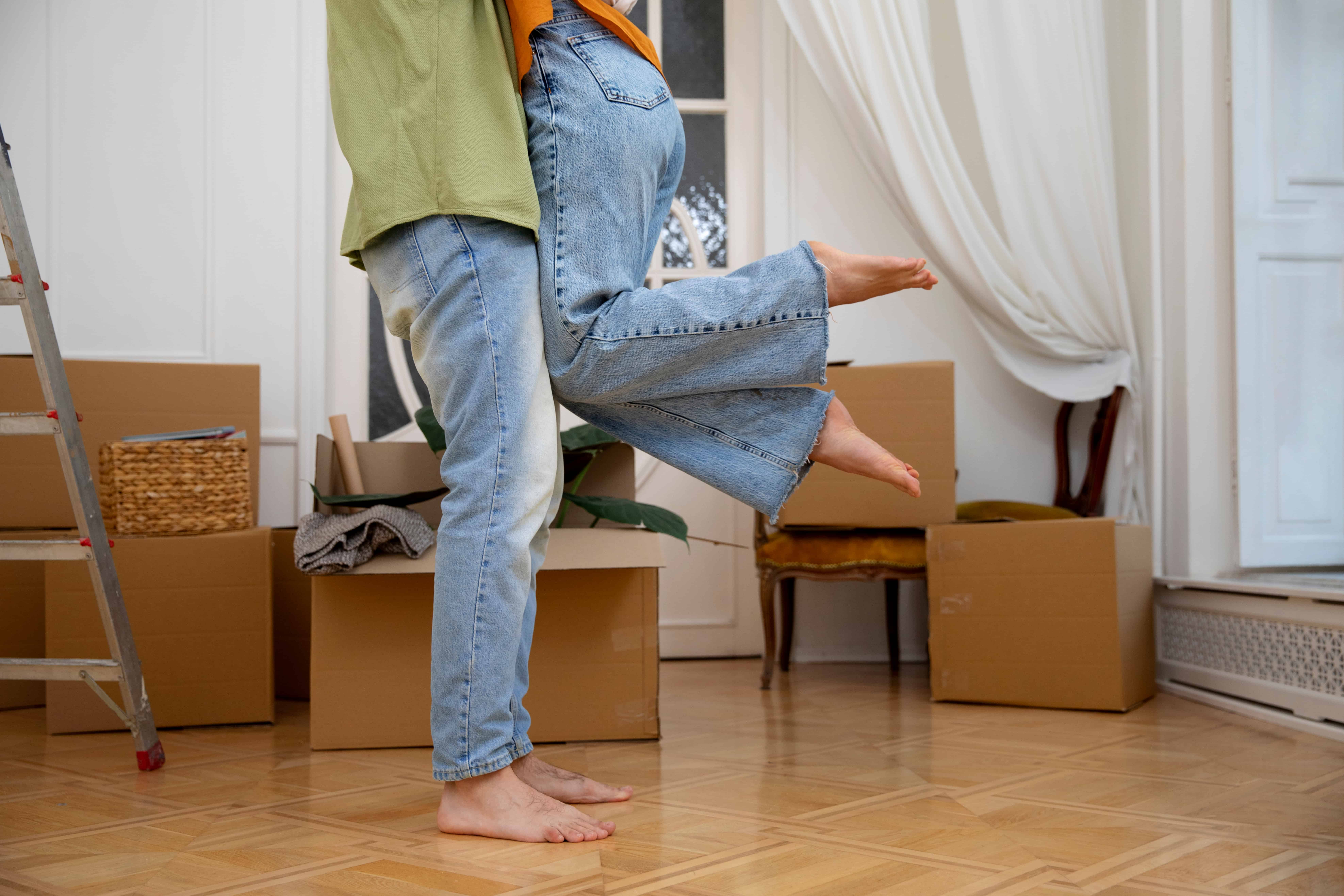 Pareja joven con ropa de verano en una habitación llena de cajas de mudanza
